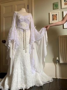 a woman in a white wedding dress is holding onto the back of her gown, which she has on display