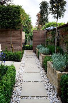 an outdoor garden with stone walkways and plants on either side, along with wooden fences