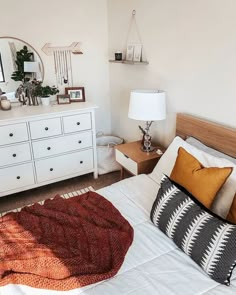 a bedroom with a bed, dresser and mirror on the wall next to each other