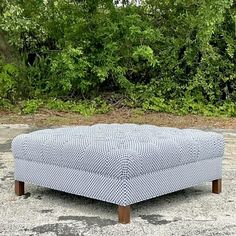 a blue and white ottoman sitting on top of a cement ground next to some trees