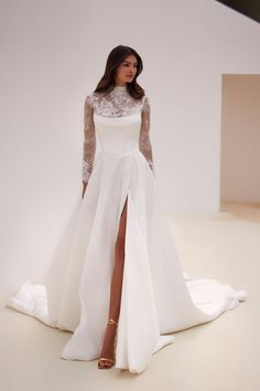 a woman in a white wedding dress with a high slit skirt and sheer lace sleeves