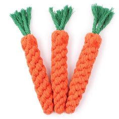 three orange carrots with green tops on a white background, one is knotted and the other is made out of rope