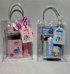 two clear bags with tags on them sitting next to each other in front of a white wall