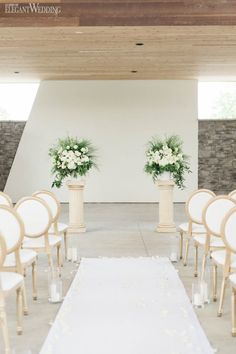 the aisle is lined with white chairs and flowers