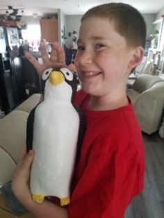 a young boy holding a stuffed penguin in his hands