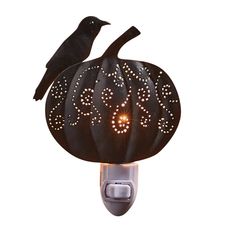 a black bird sitting on top of a pumpkin shaped night light with lights in it