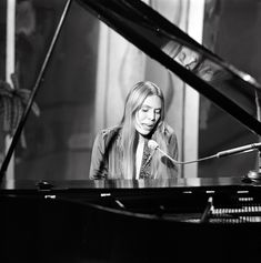 a woman sitting at a piano with a microphone in her hand