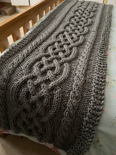 a bed with a blanket made to look like an intricate cabled design on it