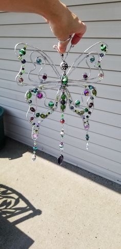 a hand is holding a glass butterfly ornament in front of a garage door