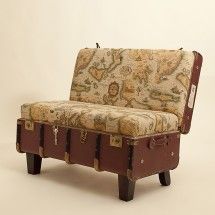 an old suitcase sitting on top of a wooden table next to a couch with a map print upholstered on it