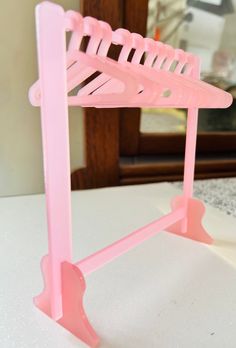 a pink plastic rack sitting on top of a white table next to a mirror and door