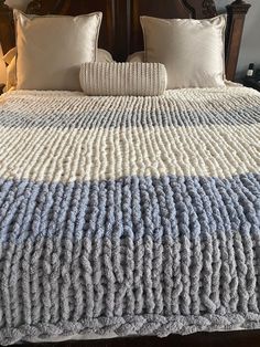 a large bed with two pillows on top of it and a blanket over the headboard