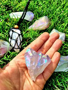 someone is holding some crystals in their hand on the grass with other rocks and stones around them