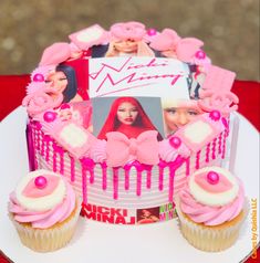 there is a cake with pink icing and pictures on the frosting next to cupcakes