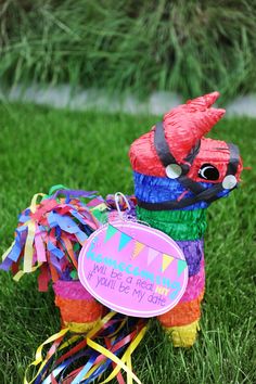 a colorful stuffed animal with a sign on it's back sitting in the grass