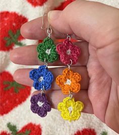 four crocheted flowers are being held by someone's hand