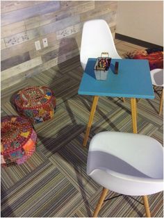 two white chairs and a blue table in a room with colorful rugs on the floor