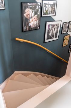 a spiral staircase with pictures on the wall and framed photos on the wall above it