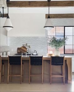 a kitchen with an island and bar stools next to the counter top in front of a window