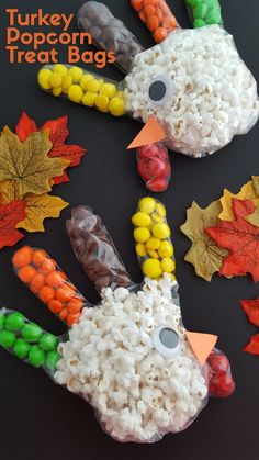 a turkey made out of candy corn and maple leaves on a black table with other fall decorations