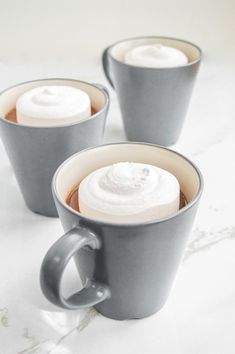 three coffee mugs with whipped cream in them