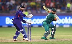 two men in green and purple uniforms playing a game of cricket