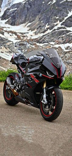 a black motorcycle parked on top of a dirt road next to a snow covered mountain