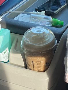 an empty cup in the back seat of a car with bottles and other items inside