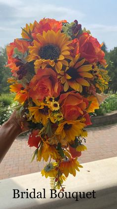 a bridal bouquet with sunflowers and other flowers in the foreground on a brick walkway