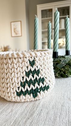 a crocheted basket with a christmas tree on the front sitting on a table