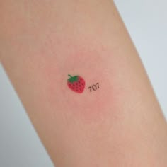 a small strawberry tattoo on the arm with the word tot written below it,