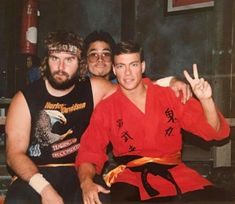 three men sitting on a bench posing for a photo with their hands in the air