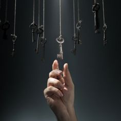 a hand reaching up to a bunch of keys that are hanging from the ceiling in front of them