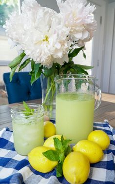 some lemons and limeade are sitting on a table with flowers in the background