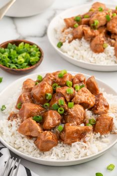 two plates filled with chicken and rice on top of a white tablecloth next to bowls of green onions