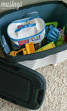 an open suitcase filled with toys on the floor next to a carpeted floor and wall