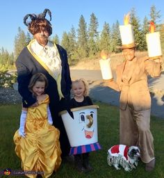 two children and an adult are dressed up as characters from beauty and the beast with candles in their hands