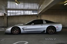 a silver sports car parked in an empty parking garage with no one around it,