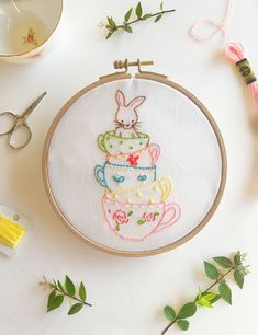 a cross stitch pattern with some scissors and other crafting supplies surrounding it on a white surface