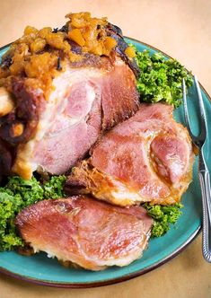 a blue plate topped with ham covered in toppings and broccoli next to a fork