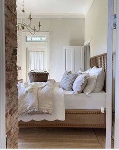 a bed with white linens and pillows in a bedroom next to a brick wall