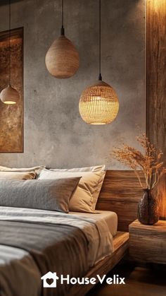 a bed sitting under two hanging lights in a bedroom next to a table with flowers