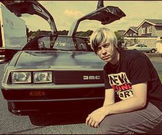 a man sitting on the ground next to a car