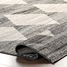 an area rug on the floor with a checkerboard pattern in grey and white