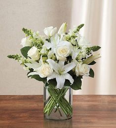 a vase filled with white flowers on top of a wooden table