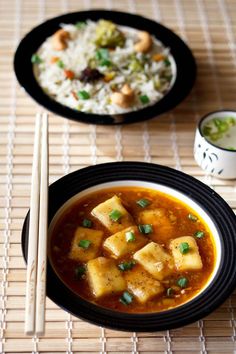 two bowls filled with food next to chopsticks