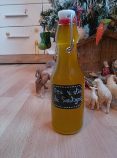 a bottle of mustard sitting on top of a wooden floor next to toy sheep and christmas tree