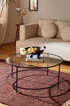 a living room with a couch, coffee table and flowers on the rug in front of it