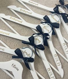 six bridesmaid spoons with black bows and name tags on them are arranged in a row