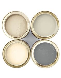 four different colors of paint sitting on top of each other in metal cans with lids